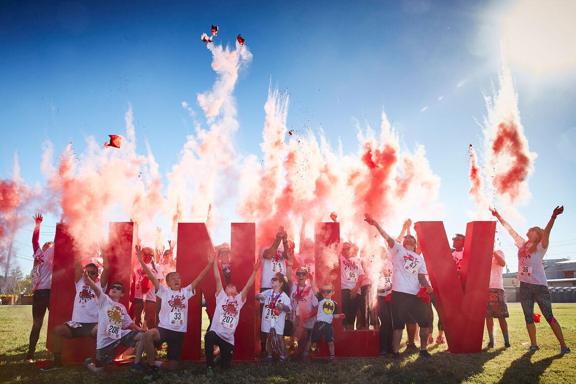 A group of people being covered by smoke bombs in front of U-N-L-V signage