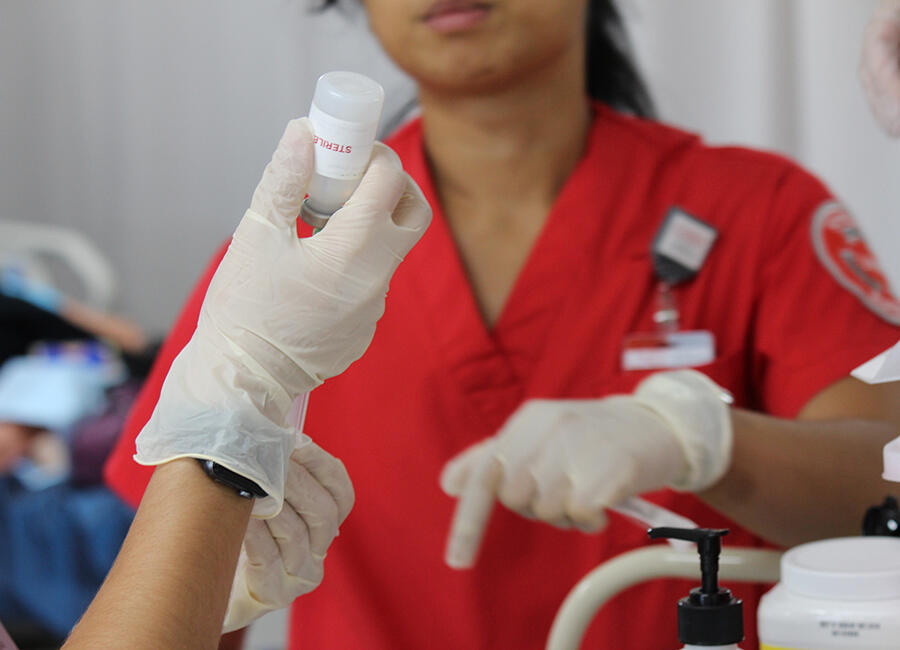 Female medical professional pointing and a vial being held up