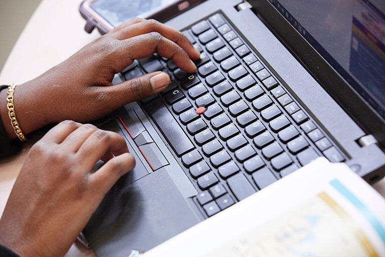 Close up of someone's hands on a black laptop
