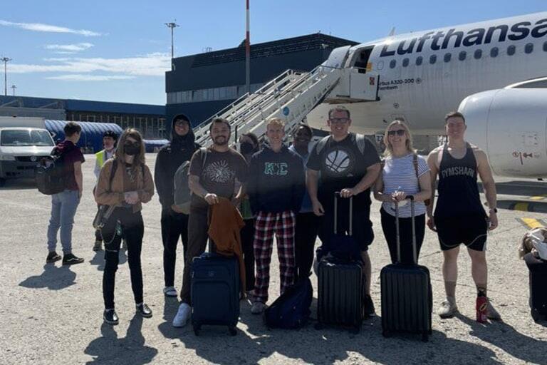 Students pose in front of a plane