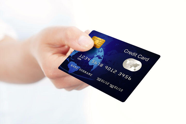 A person holding up a credit card