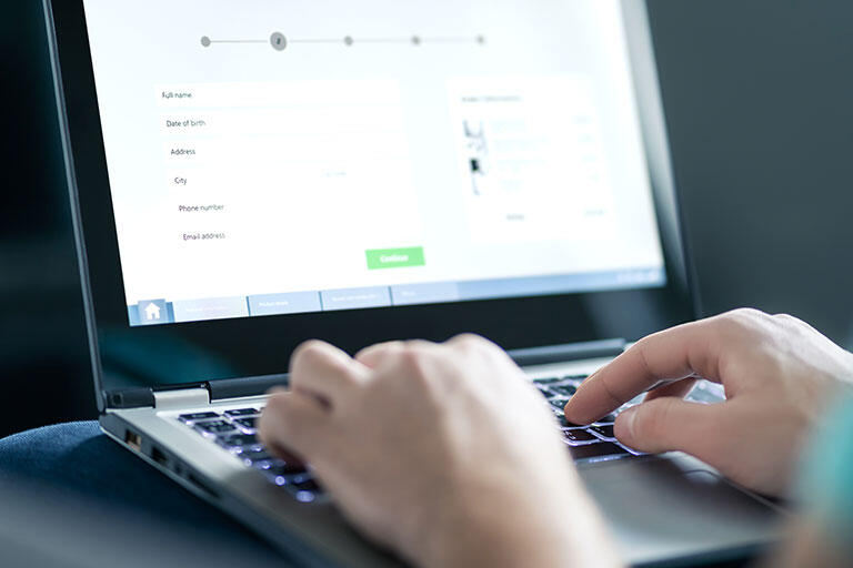 A person's hands on a keyboard typing on a laptop