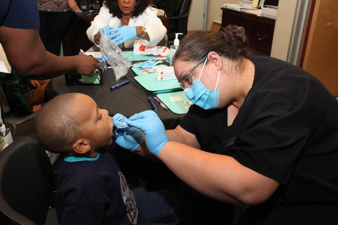 Woman with dental gear looking into child's mouth