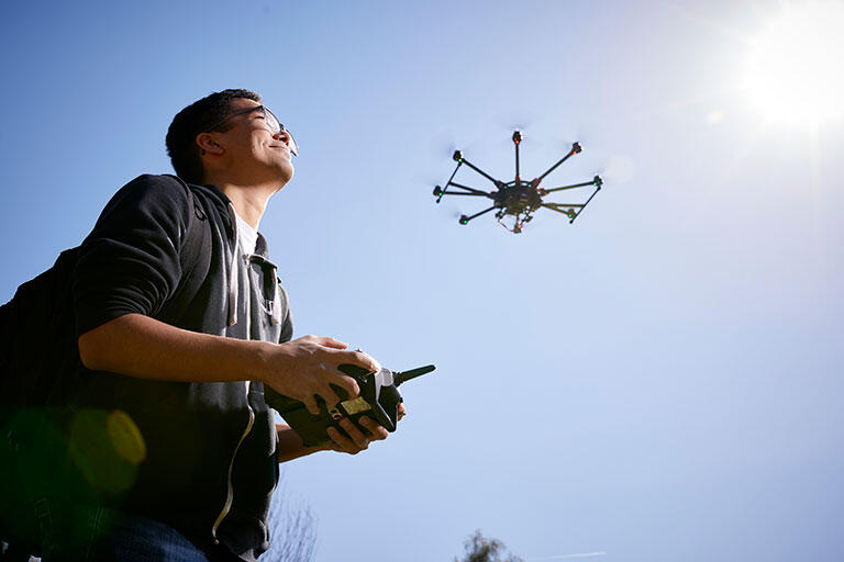 A person piloting a drone above him