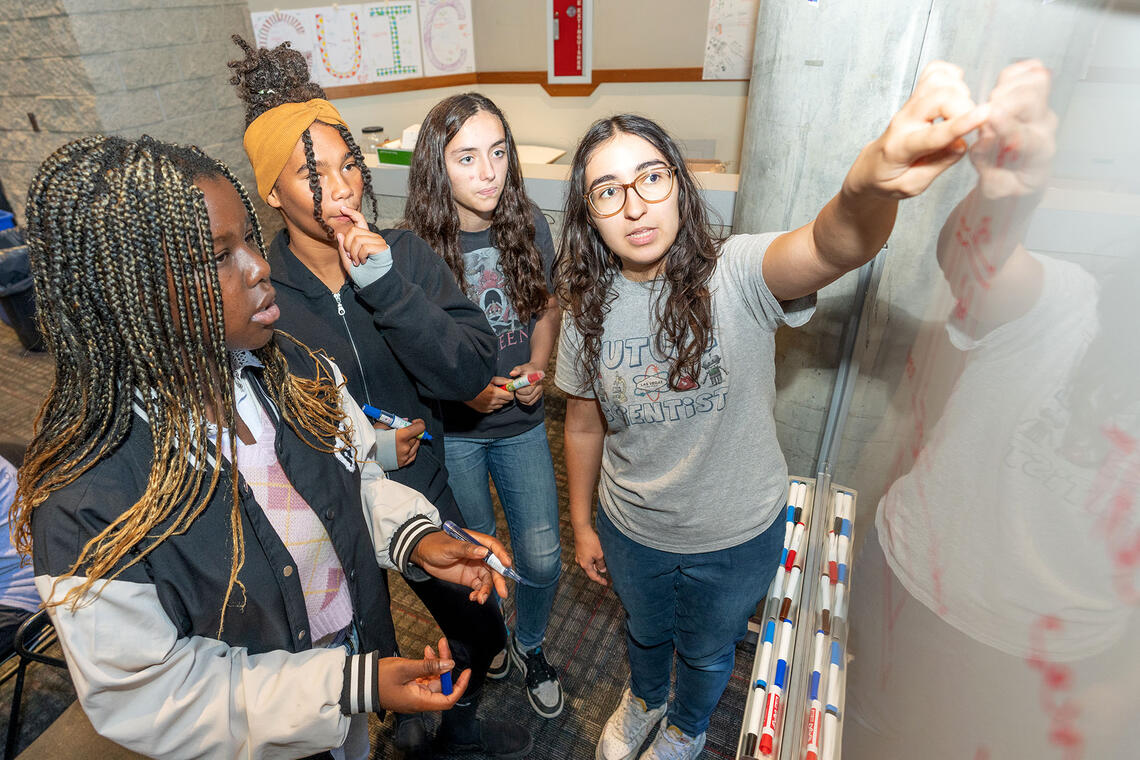 group of female students using whiteboard for project
