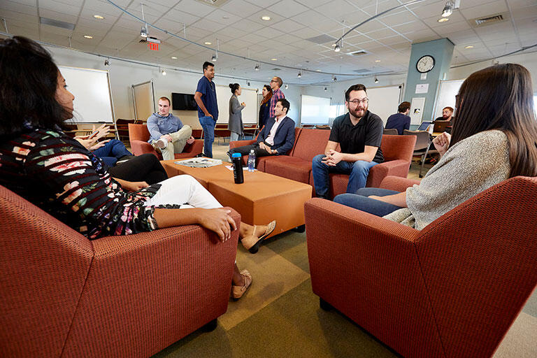 People sitting down in chairs and talking in a lounge area