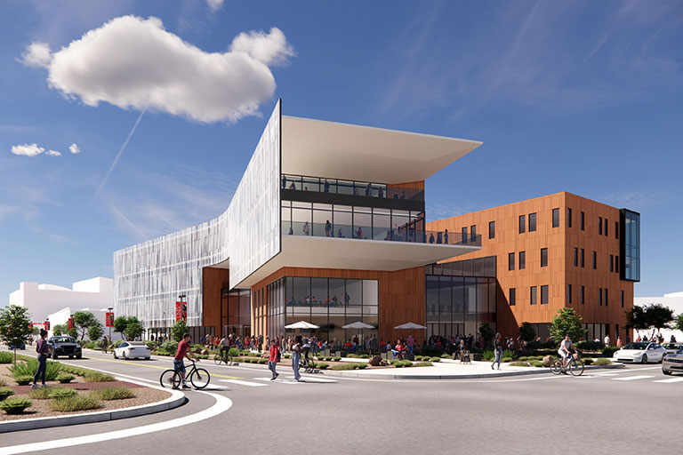 A large landscape view of the exterior of a large two story building that has large glass windows