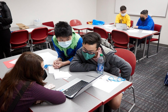 Three students looking at a laptop