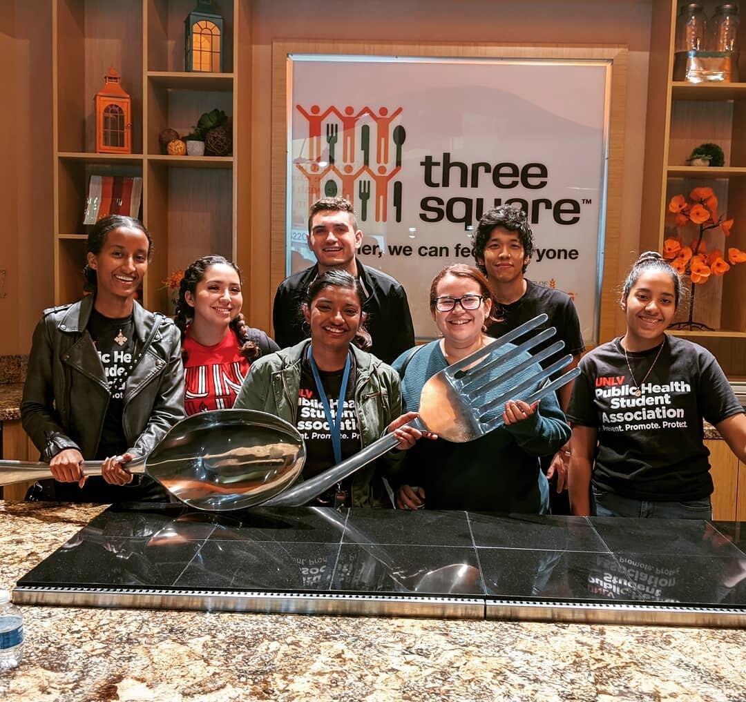 group of people holding a large spoon and fork 