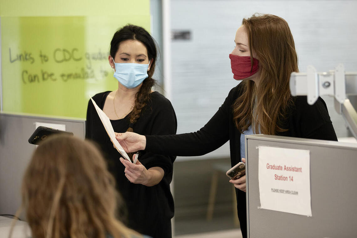 two people wearing masks while reading a document