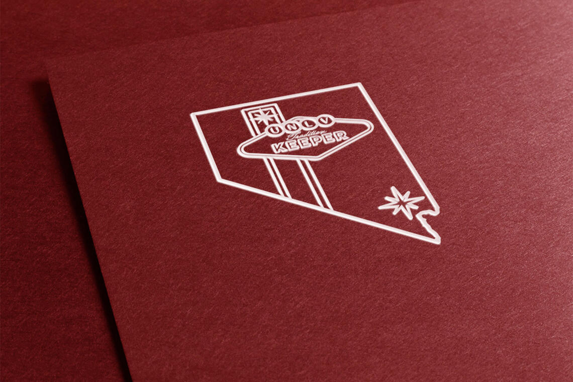 An embroidery of an outline of the Nevada state with the words "UNLV Tradition Keeper" on a red folder