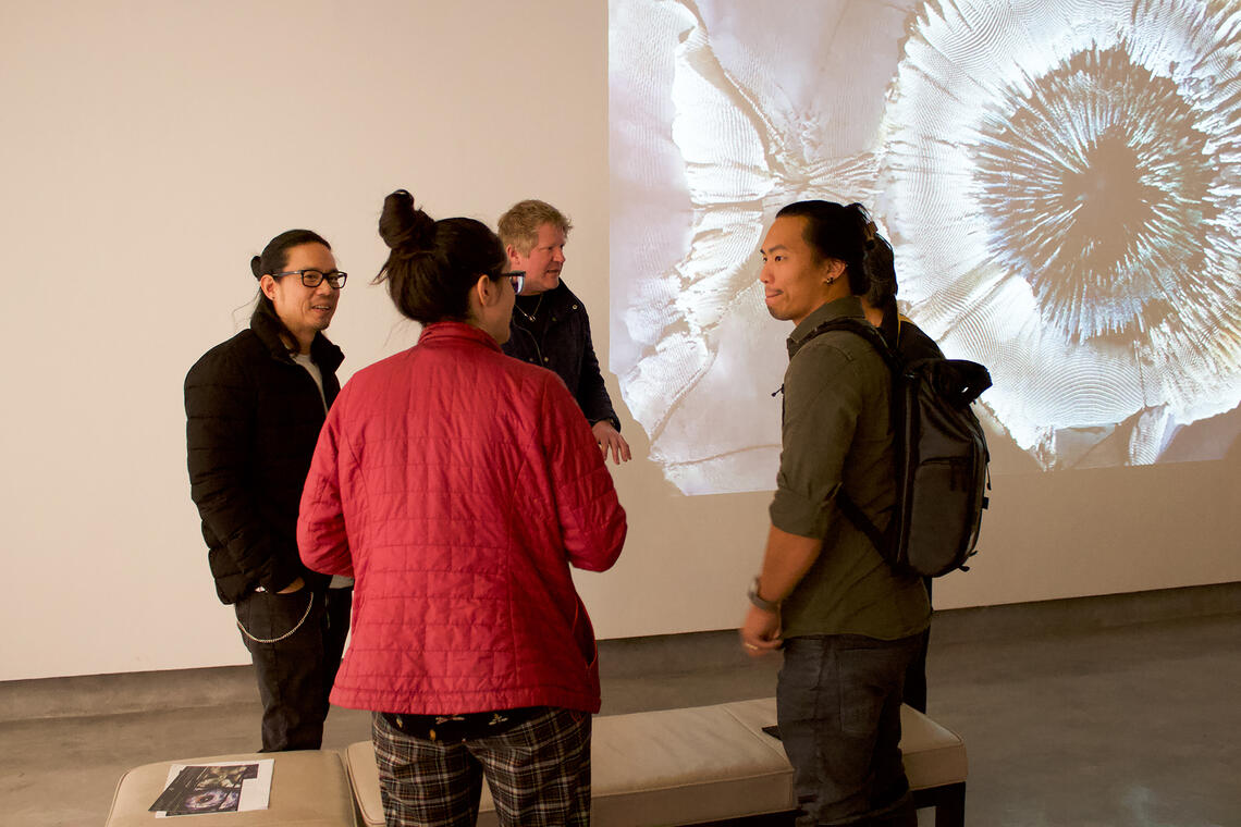 Four people having a discussion on the art displayed 