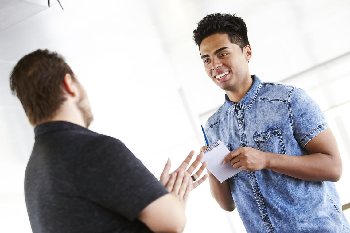 two people talking with a card in one person's hand
