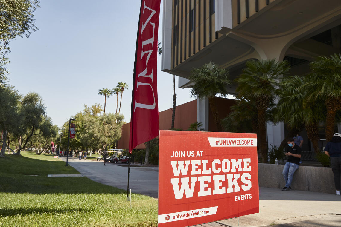 Outdoor sign saying "Welcome Week" next to UNLV flag