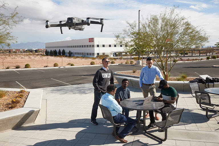 four people working on a flying drone