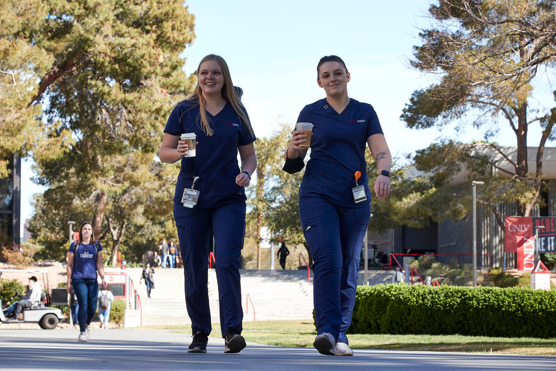 Two people wearing scrubs walking in the hallway