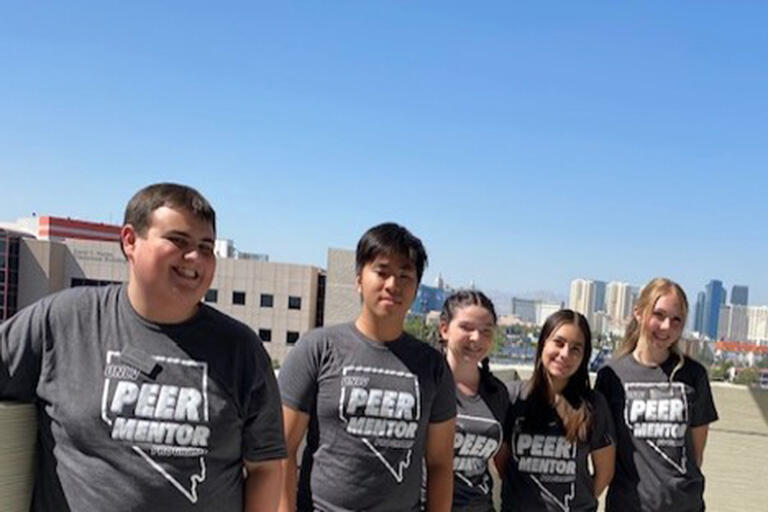 five people having their photo taken on a rooftop