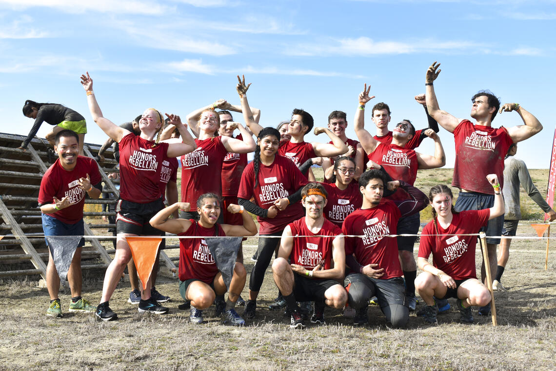 a group of people outdoors posing and flexing arms for a photo