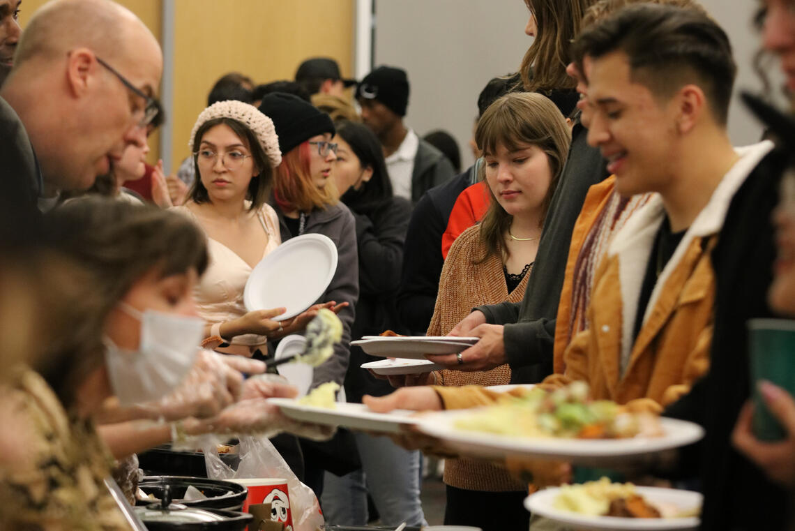 people in line with plates grabbing food