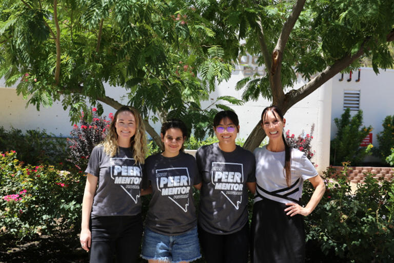 four students having their photo taken under the tree