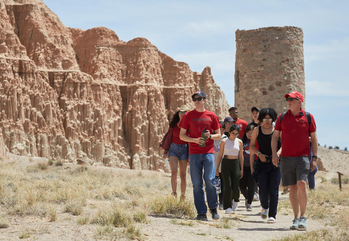 a group of students wearing red and walking an outdoor trail