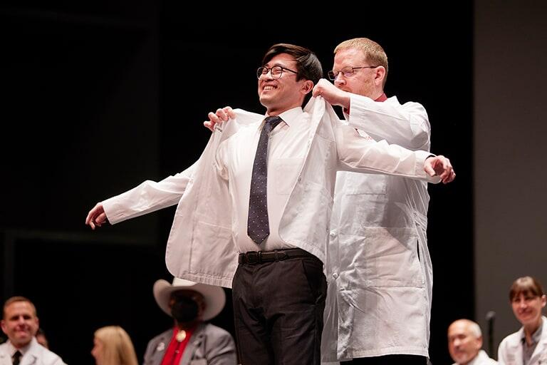 Graduate receives white lab coat during ceremony