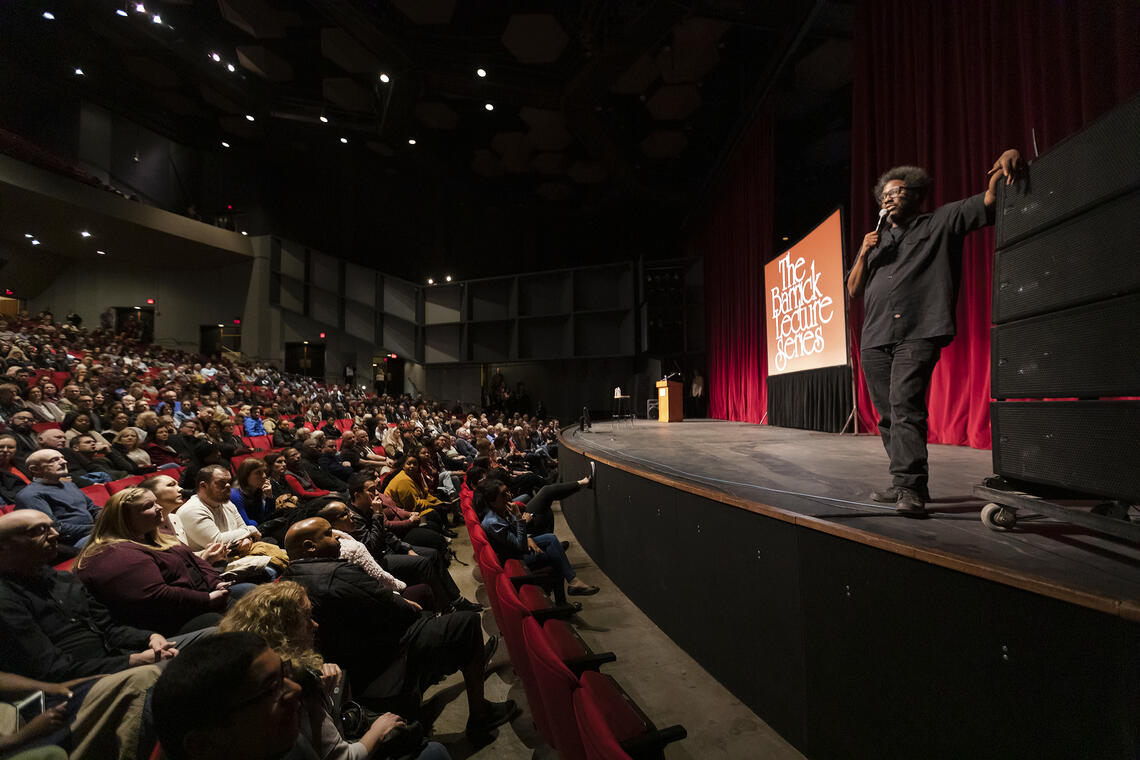 Photo of sociopolitical comedian W. Kamau Bell delivering a presentation to a packed audience at the UNLV Performing Arts Center for the Barrick Lecture Series.