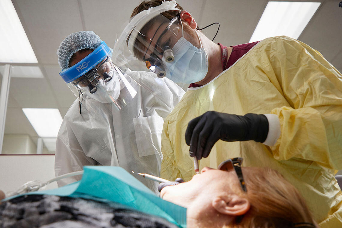 Two hygienists looking at a patient's teeth 