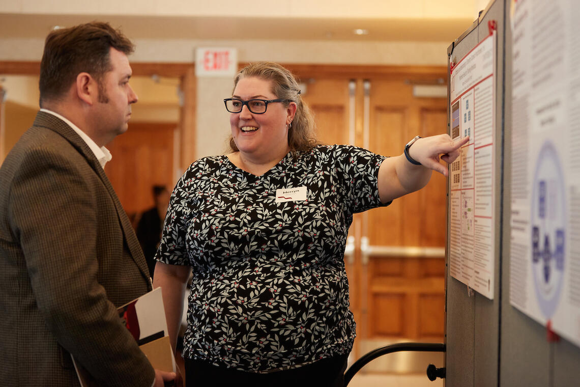 woman pointing at a board and facing another person