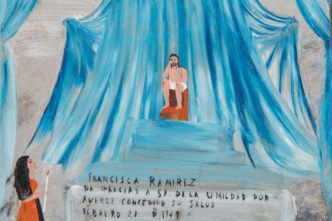 A painting of a bearded man with bloodied knees sitting on a tall orange chair on a blue podium. He is gorgeously framed with grand, sweeping curtains in the same shade of blue as the podium. A woman stands at the bottom of the podium looking up at him with a lit candle in her hand. Roughly-sketched text next to her reads, &quot;Francisca Ramirez. La Gracias a sr. de la umildad por averle conce[illegible] su salud. Febrero 21 D 1949.”