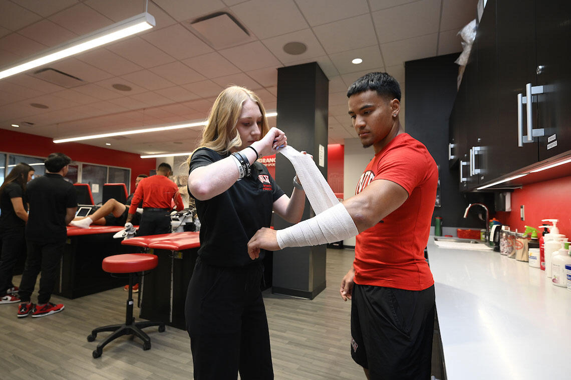 A woman wrapping bandage around a man's arm