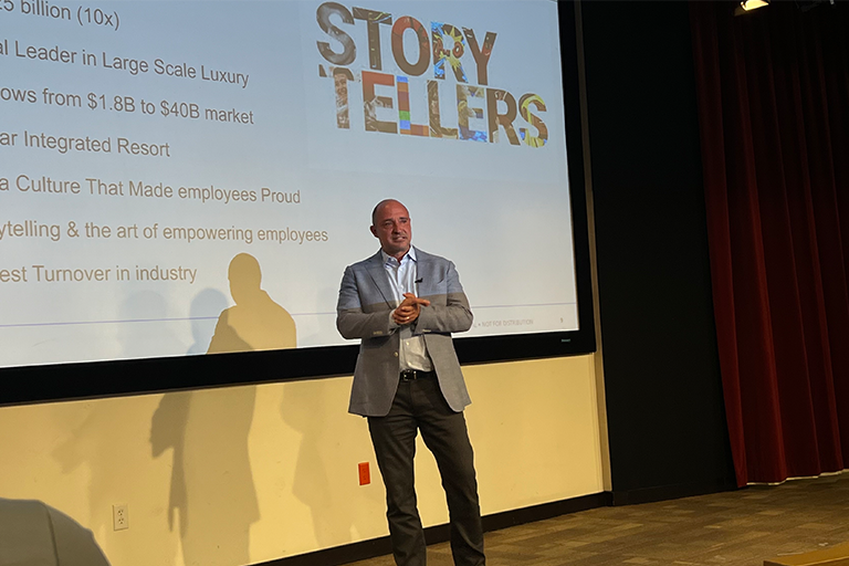 A man on a stage in front of a presentation board