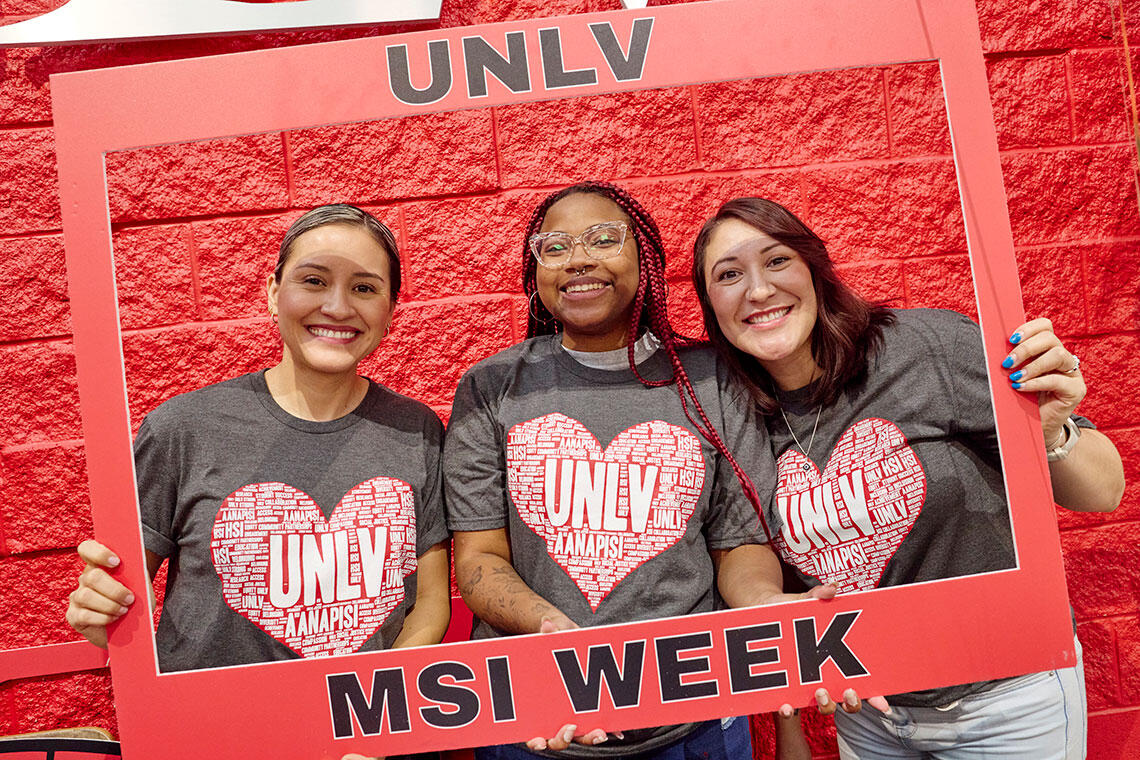 Three women holding a photo prop with the words "U-N-L-V MSI Week" on it