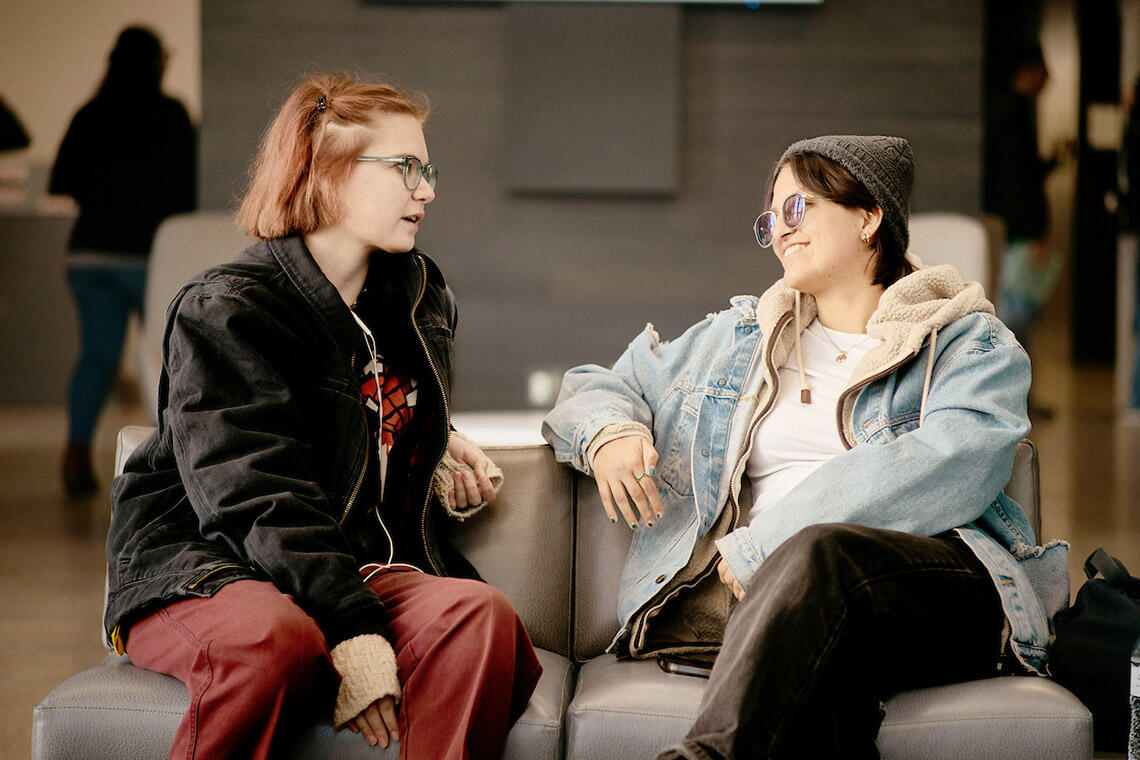 Two people talking to each other while sitting down on chairs