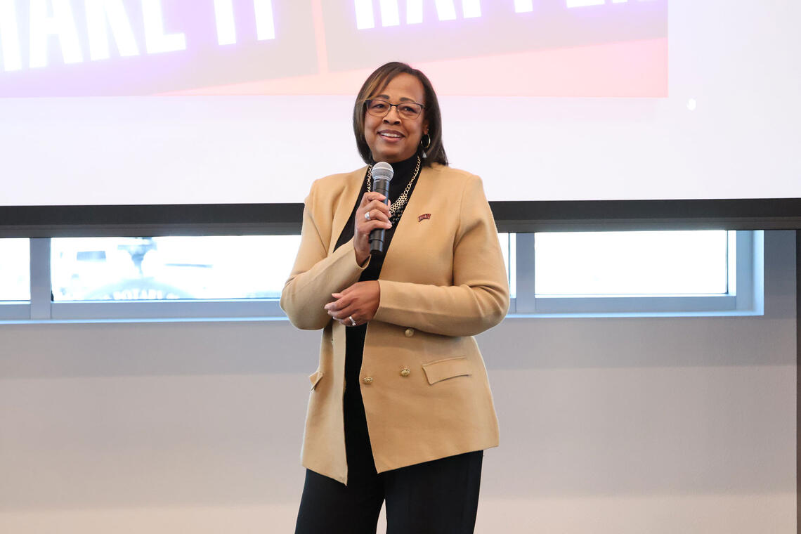 A woman standing in front of the room while holding a microphone