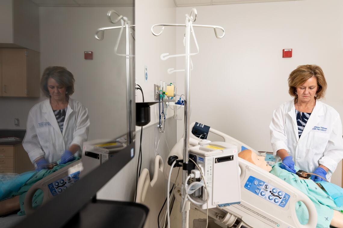 Healthcare professional standing over a mannequin patient