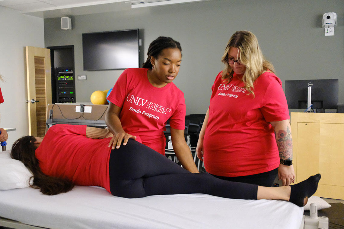 Two students examining a person on a table