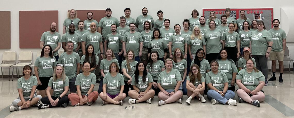 A group of teachers at a workshop all wearing the same green shirt.