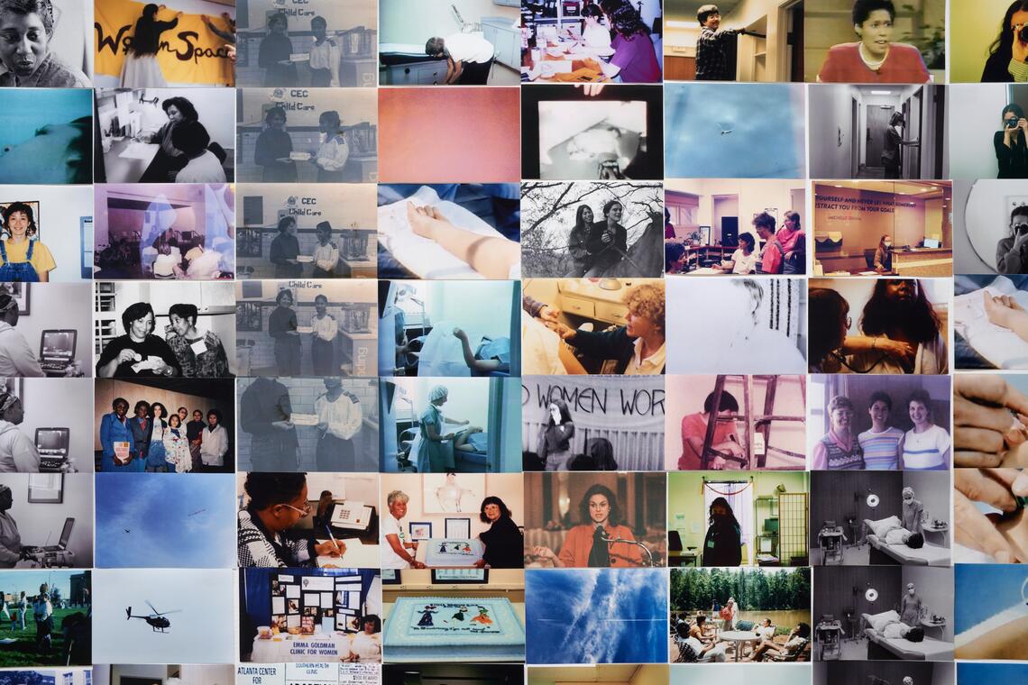 We are looking at a field of photographs installed tightly side by side. Most of them are images of women performing an array of activities--leaning on a ladder, speaking into a microphone, making notes at a desk, lying on a medical examination table in a gown, etc. They seem to come from different time periods. Some are in black and white, some are in color. A few of them are photographs of helicopters flying overhead.