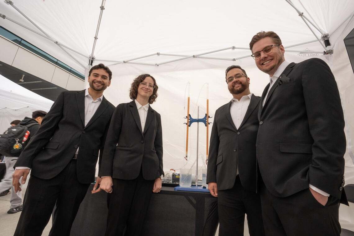 Four UNLV Engineering students pose with their working prototype inside a white event tent