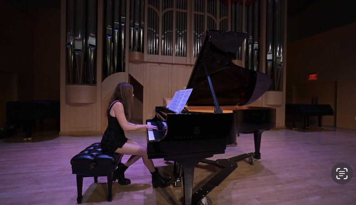 woman playing a Steinway piano in front of a pipe organ