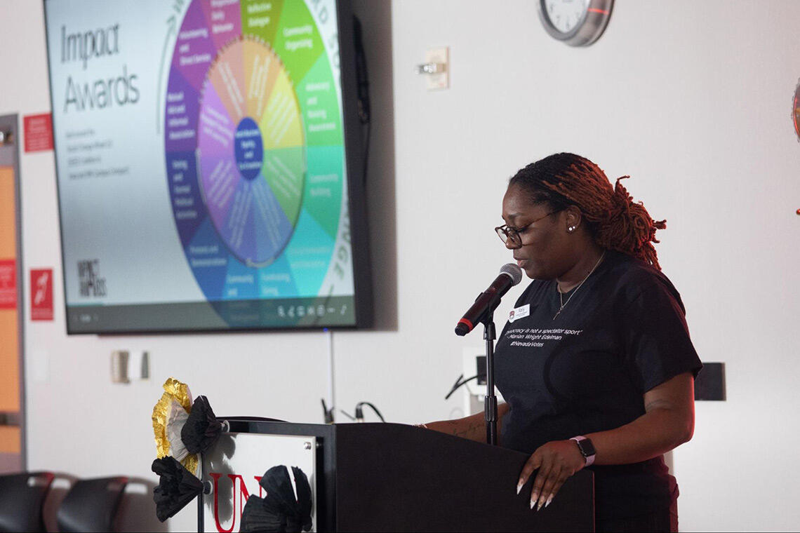 A woman standing in front of a podium and talking into a microphone.