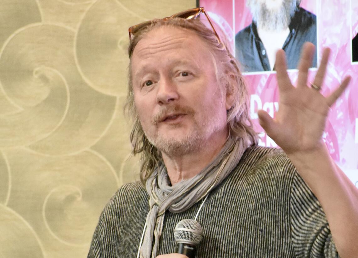 Photo of a man holding a microphone in mid sentence