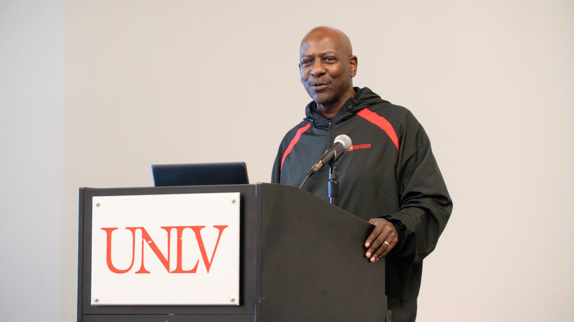 Melvin Taylor talks behind a podium with a UNLV logo