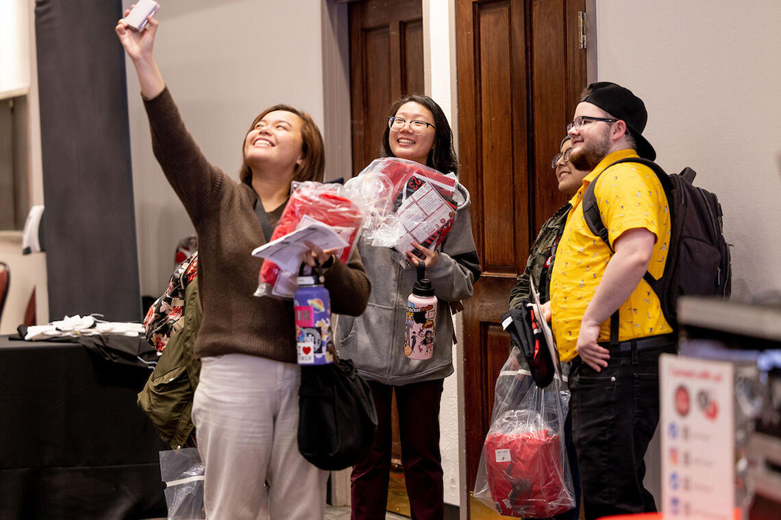 A group of students smile and take a selfie together.