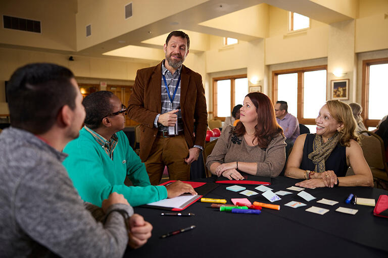 Dave Schwartz standing and speaking with a group of people seated at a table