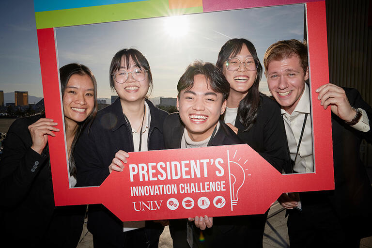 Group of students posing with a large, red President's Initiative photo frame
