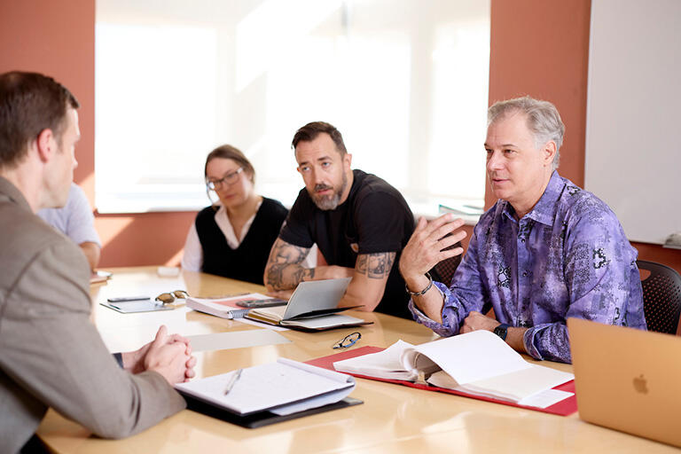 Group of four seated at a table and speaking with each other
