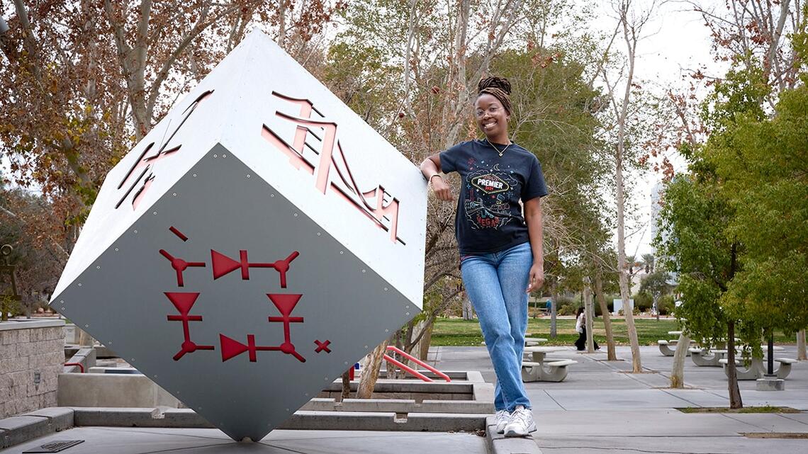 Student poses next to sculpture