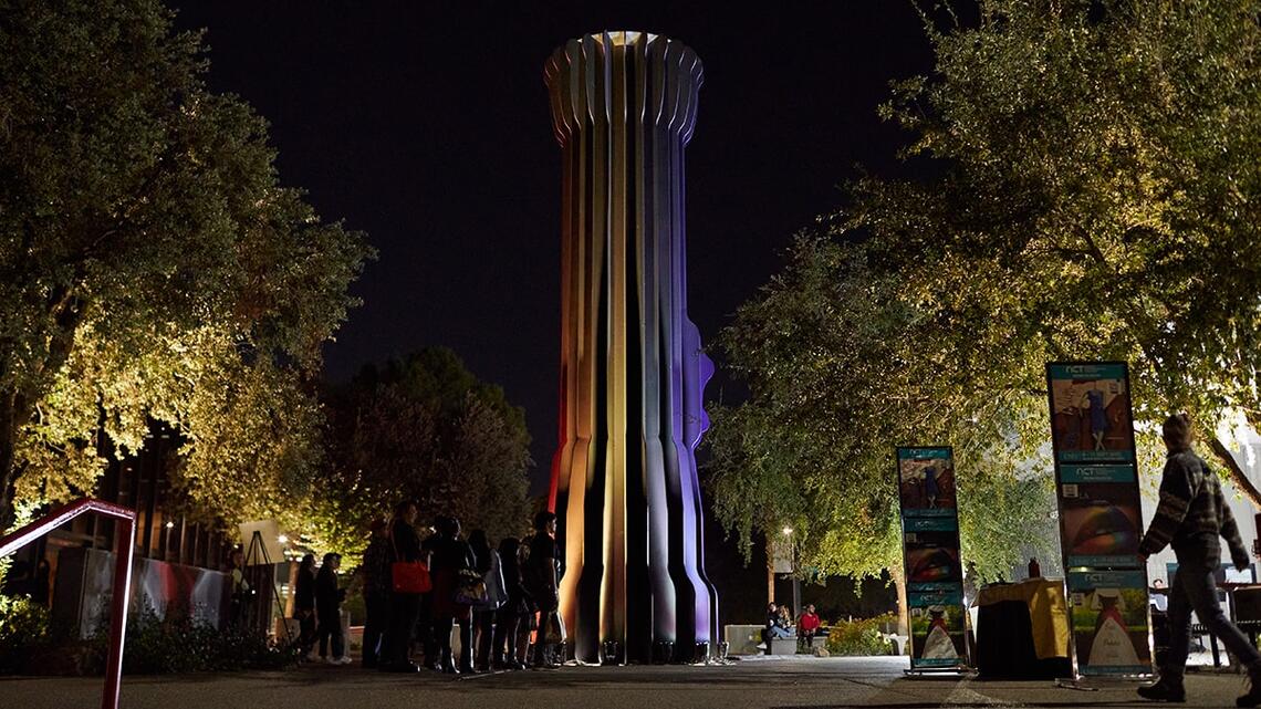 People gathered around a large flashlight sculpture